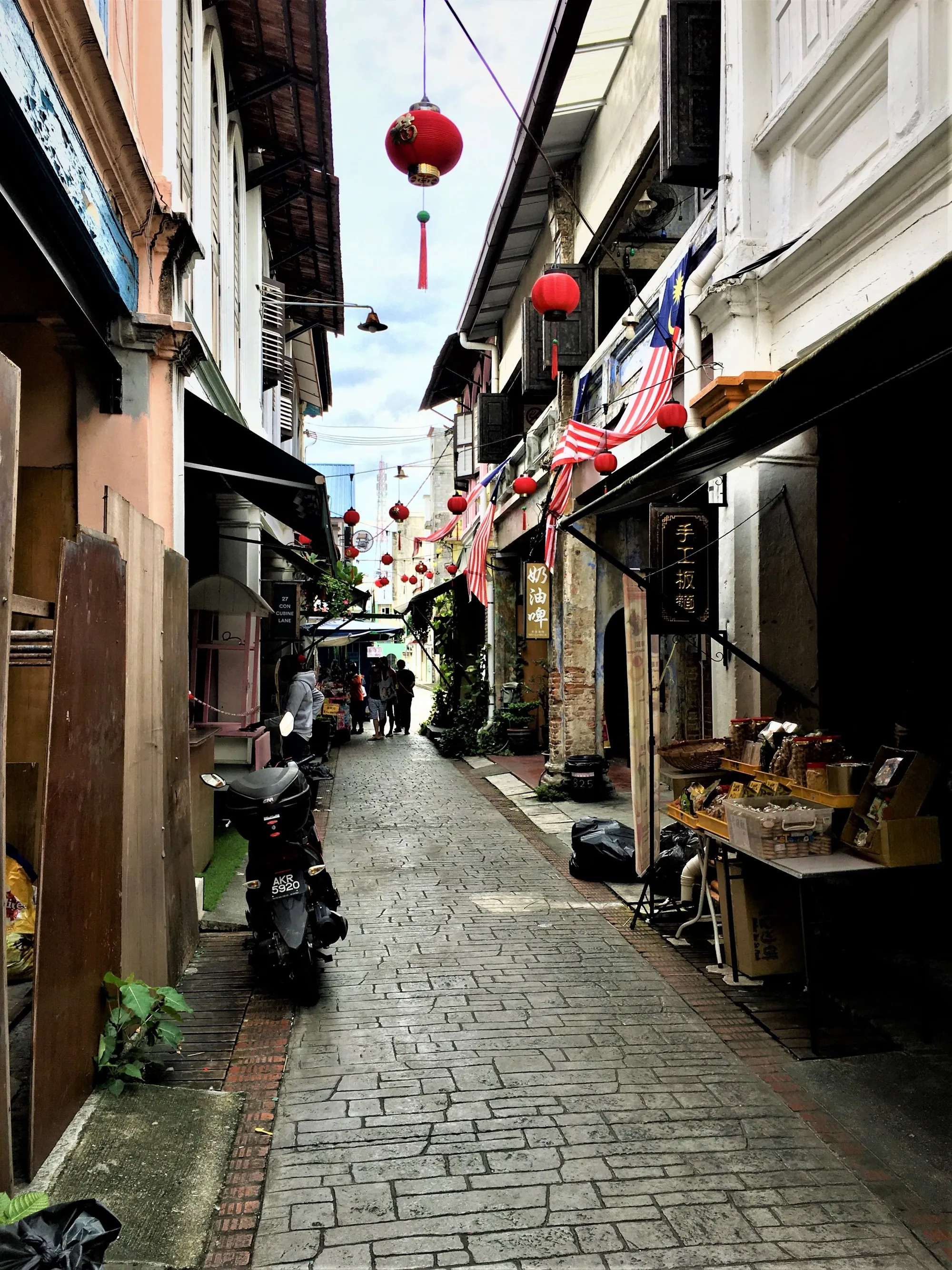 Narrow paved lane between two-storey shophouses hung with red lanterns, Concubine Lane, Ipoh