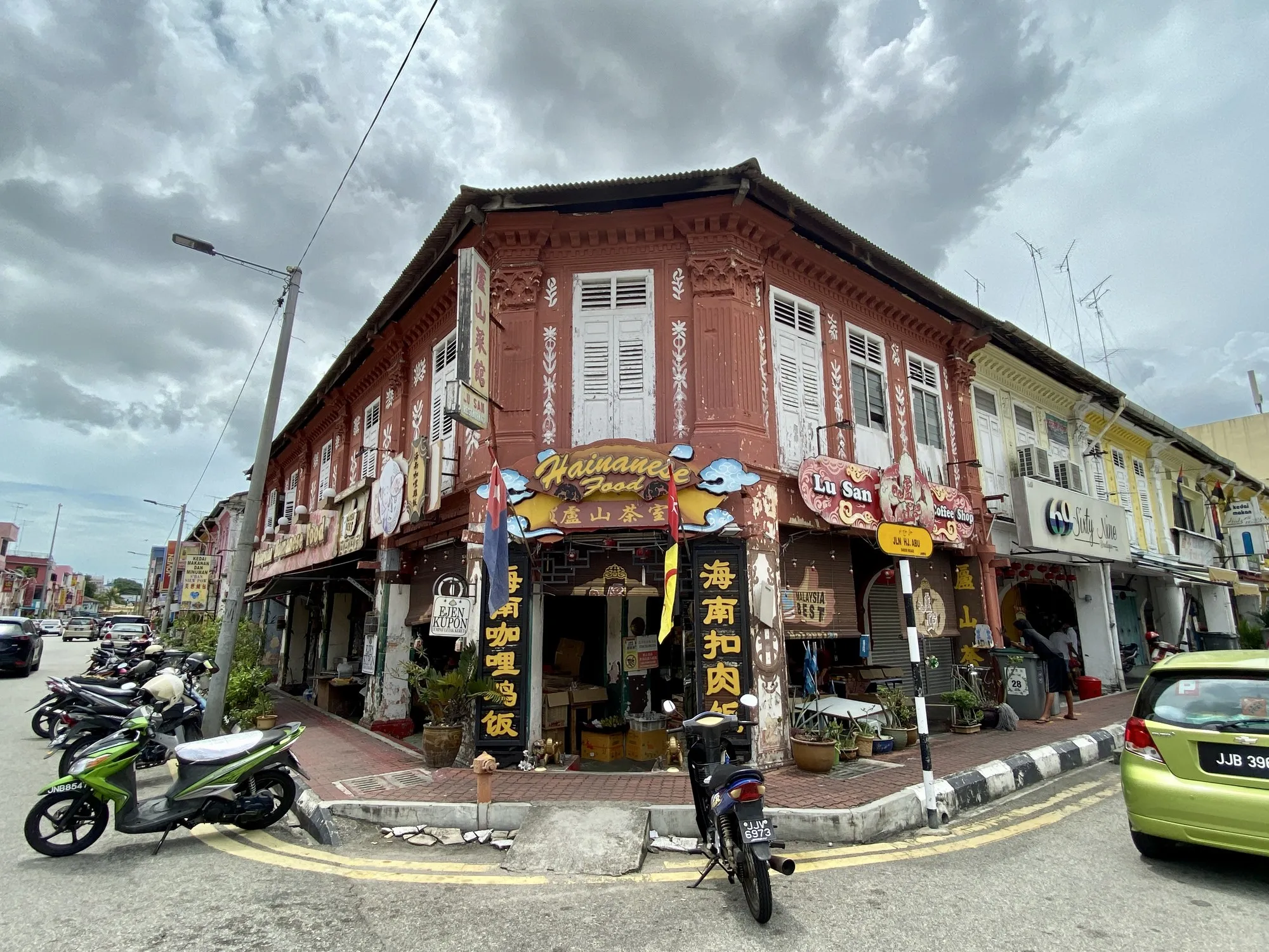 Two-storey heritage corner shophouse coffee shop with open frontage and parked motorbikes