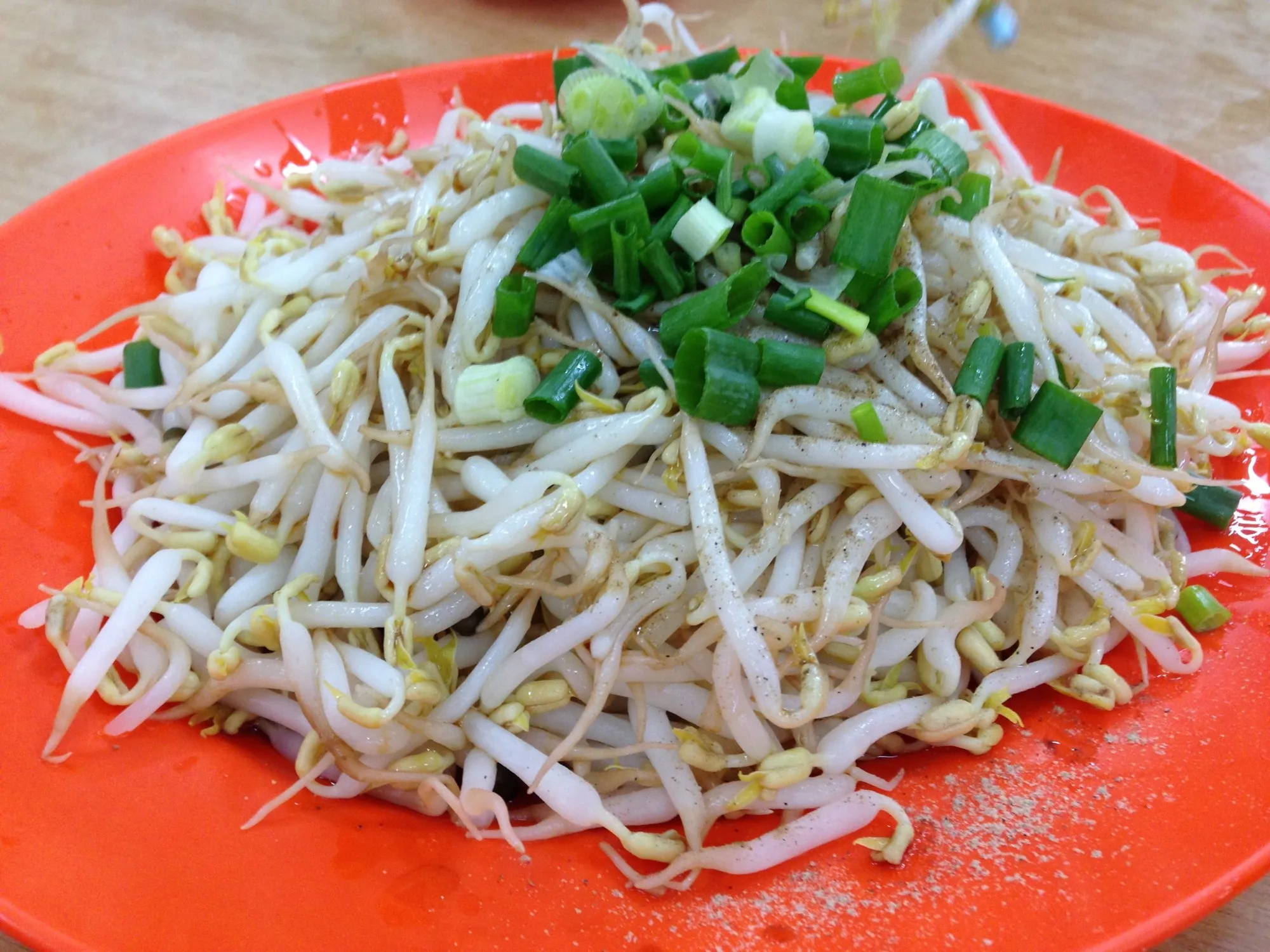 Plate of short, plump blanched bean sprouts dressed with soy sauce, oil and spring onion in Ipoh