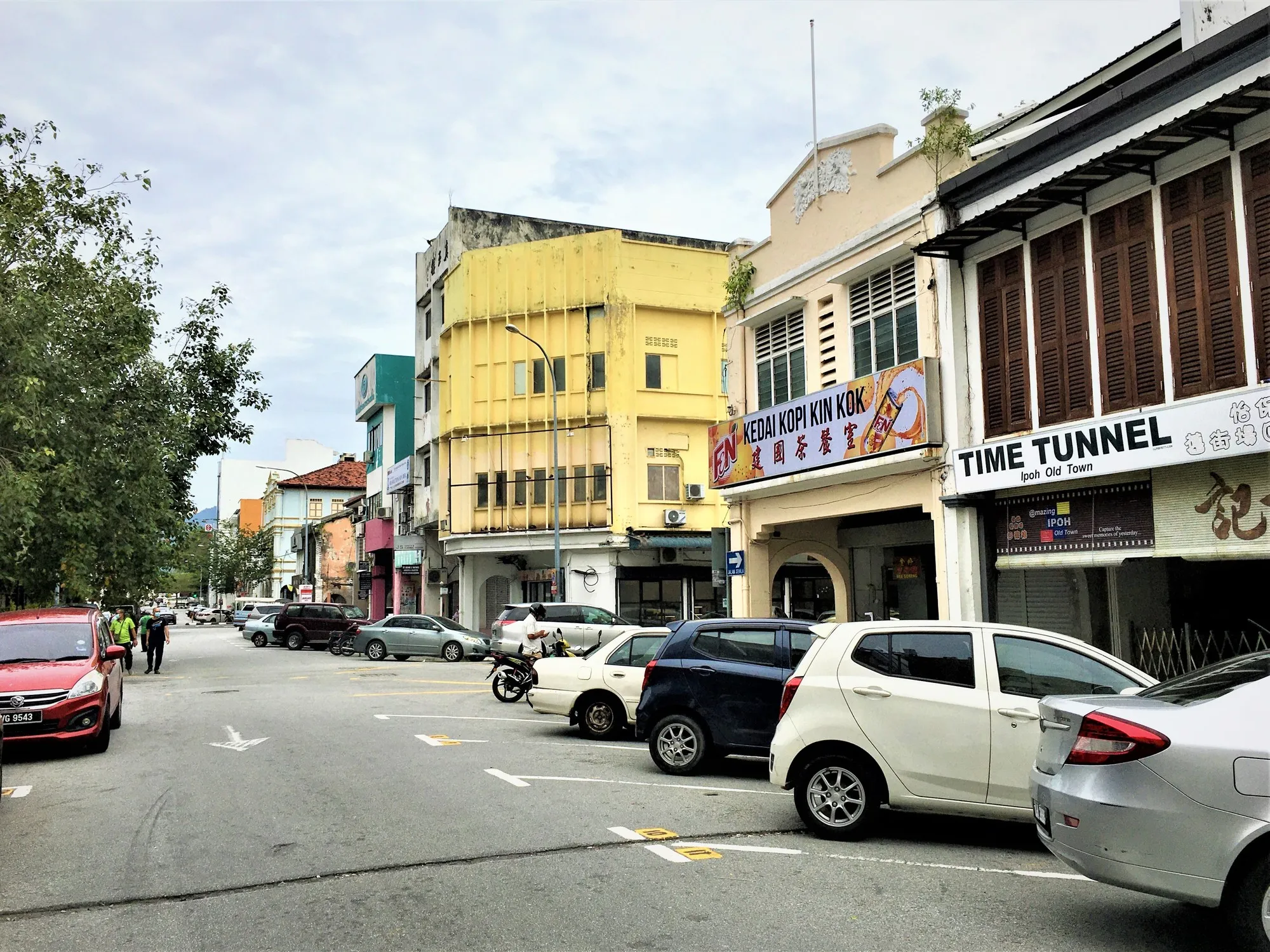 Jalan Panglima in Ipoh Old Town, with colourful two-storey shophouses and parked cars under a cloudy sky