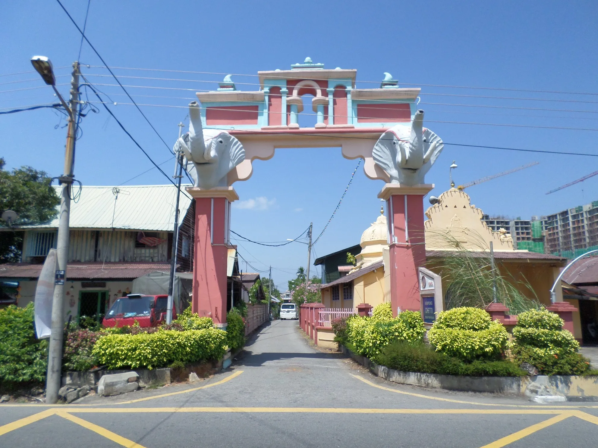 Pink arched gateway with elephant figures at the entrance to a quiet residential lane in Kampung Chetti, Melaka