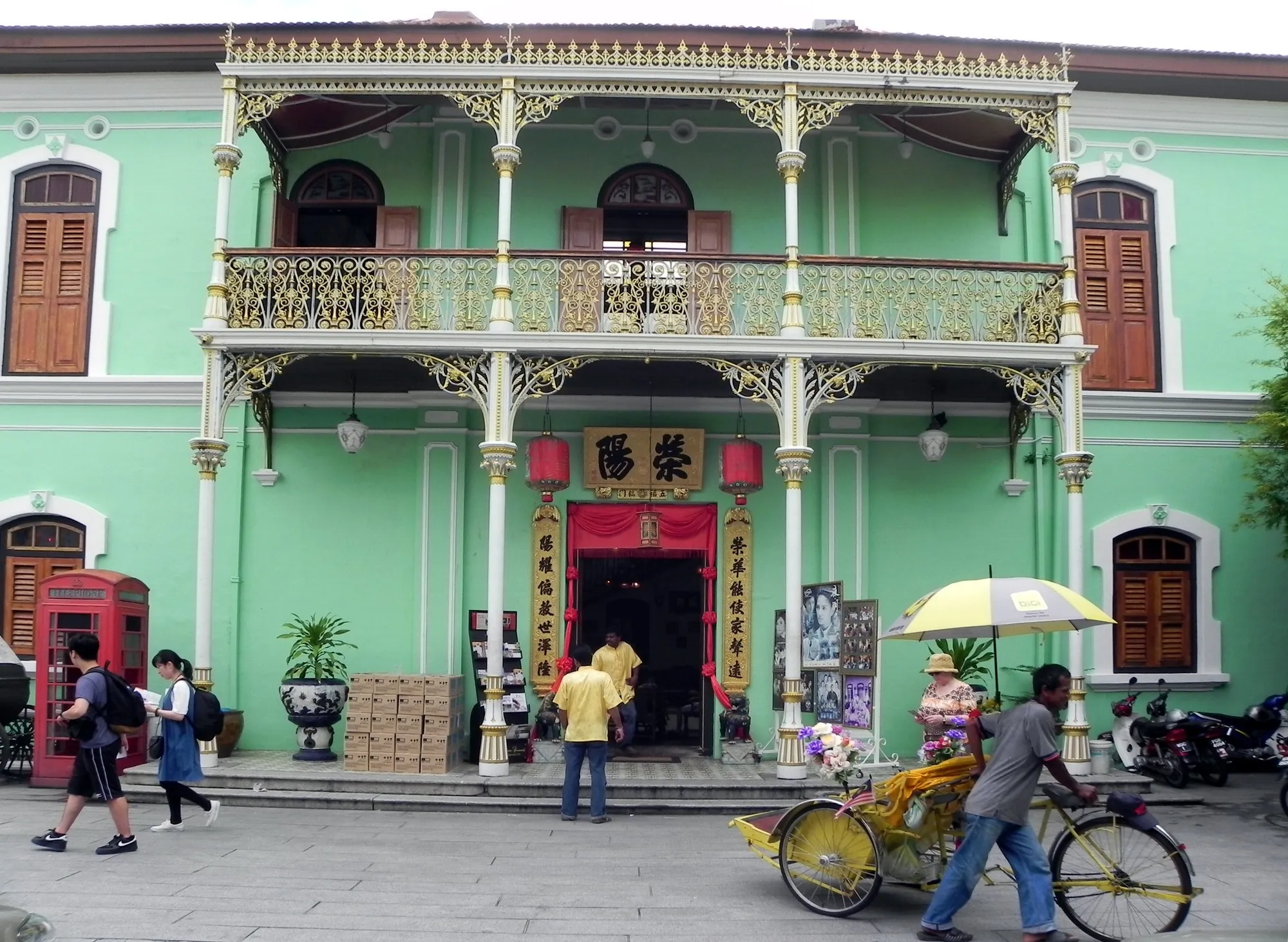 Green two-storey mansion with ornate cast-iron balconies and a red entrance in George Town, Penang