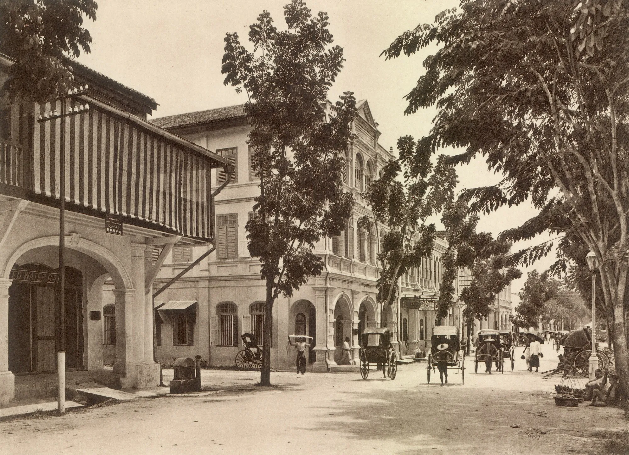 Sepia photo of Station Road, Ipoh, around 1910, with shophouse arcades, trees and rickshaws